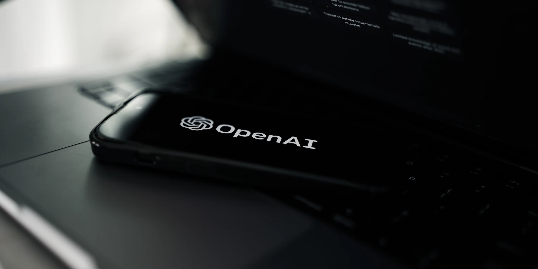 An image of a smartphone with the OpenAI logo displaying on the screen.